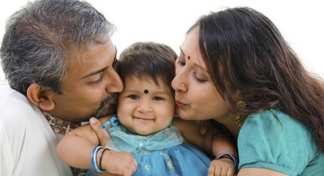 A man and a lady kissing a baby